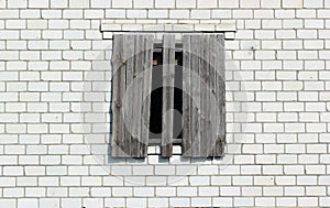 Boarded up window in a white brick wall