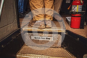 Boarding a bus - men\'s feet at top of steps reading Watch Your Step and including bus drivers feet and fire extinguisher