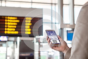 Boarding pass in smartphone. Woman holding phone in airport with mobile ticket on screen.