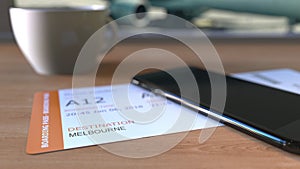 Boarding pass to Melbourne and smartphone on the table in airport while travelling to Australia. 3D rendering