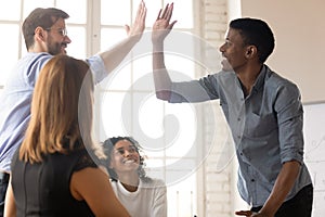 African and Caucasian buddies giving high five greeting each other photo