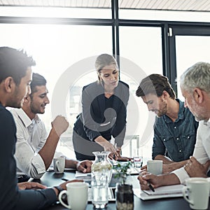 Boardroom meeting in progress. Shot of a businesswoman talking to colleagues sitting around a table in an boardroom.