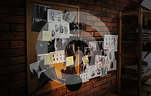 Boards with fingerprints, crime scene photos and red threads on brick wall. Detective agency