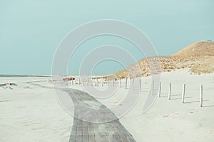 Boardwalk on a empty beach with dunes and grass in north Netherlands