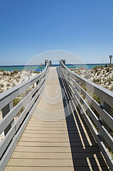 Boardwalk over the white sand dunes with a view of the blue ocean and sky at Destin, Florida