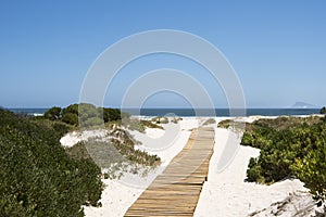 Boardwalk to the sea. Wooden planks over white sand to Atlantic Ocean, South Africa 