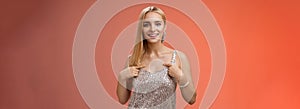 Boastful good-looking confident blond european woman in silver luxurious dress pointing herself smiling proudly bragging