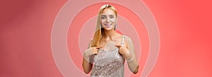 Boastful good-looking confident blond european woman in silver luxurious dress pointing herself smiling proudly bragging
