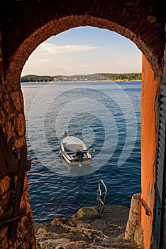 Boat in the Adriatic sea as seen from arched wall in Rovinj at sunset, Istrian Peninsula, Croatia photo