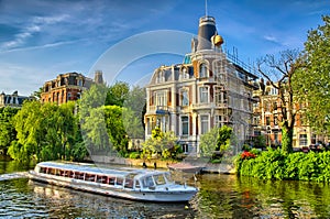 Boat on Amstel river near beautiful houses in Amsterdam, Holland