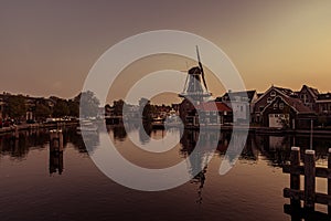 Boat anchored on a canal in Amsterdam at sunrise, windmill