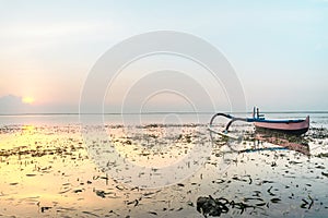 Boat Anchoring Near Beach or Seashore Full of Seaweed At Sunrise or Sunset with Yellow Pink Light Reflection on Water Surface. Sof