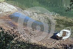 Boat ashore and mountain reflections at Scanno lake, Abruzzo, Italy