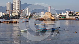 Boat on background of fishing village and city under construction. Fishing boats pass by