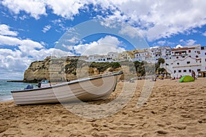 boat on beach in Carvoeiro village with colorful houses, Algarve region, Portugal