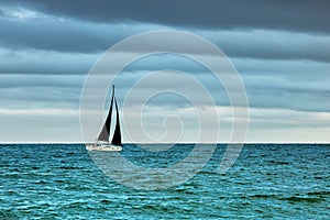 Boat with black sails on the sea in stormy weather