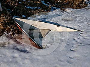 boat buried underneath the snow and ice on shore