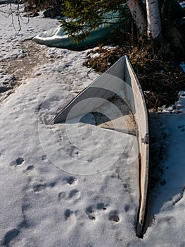 boat buried underneath the snow and ice on shore