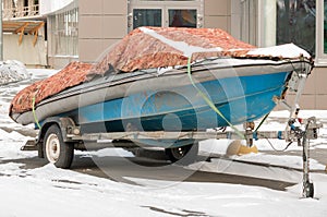 Boat on a car trailer under a tarp