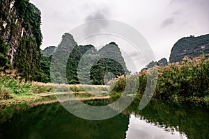 Boat cave tour in Trang An Scenic Landscape formed by karst towers and plants along the river (UNESCO World Heritage Site). It's