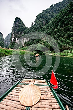 Boat cave tour in Trang An Scenic Landscape formed by karst towers and plants along the river (UNESCO World Heritage Site). It's