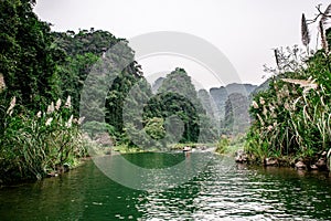 Boat cave tour in Trang An Scenic Landscape formed by karst towers and plants along the river (UNESCO World Heritage Site). It's