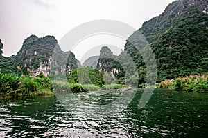 Boat cave tour in Trang An Scenic Landscape formed by karst towers and plants along the river (UNESCO World Heritage Site). It's