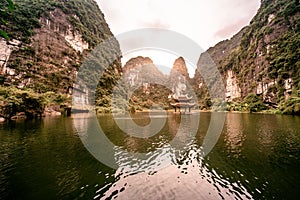 Boat cave tour in Trang An Scenic Landscape formed by karst towers and plants along the river (UNESCO World Heritage Site). It's