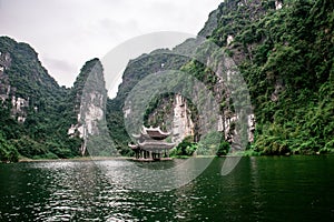 Boat cave tour in Trang An Scenic Landscape formed by karst towers and plants along the river (UNESCO World Heritage Site). It's