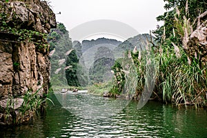 Boat cave tour in Trang An Scenic Landscape formed by karst towers and plants along the river (UNESCO World Heritage Site). It's