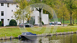 A boat on the city lake, autumn, along with cars parked on the street, white residential buildings and green grass