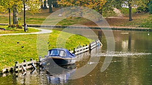 A boat on the city lake, autumn, along with cars parked on the street, white residential buildings and green grass