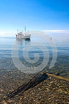 Boat coming to shore in clear water (lake Baikal)