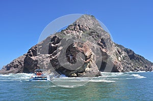 Boat crossing in front of a large rock formation photo