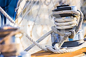 Boat deck of sailing yacht with close-up of moored nautical rope at winch