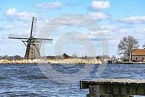 A boat dock in the rough water of lake De Rottemeren with the windmill De Korenmolen in the background on a sunny but stormy day 2