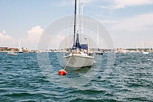 Boat docked in bay. Open water with sailboat anchored.