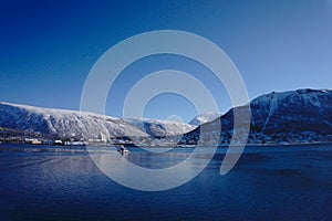 Boat driving through water with snow mountains behind