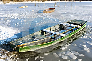 Boat at the edge of a frozen river on a sunny winter day