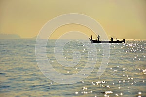 Boat with fishermen in the sea at sunset, silhouette.