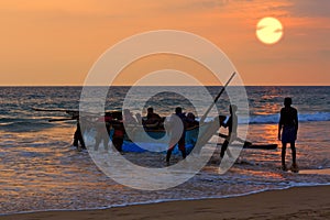 Boat with fishers on sunset background