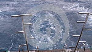 Boat is floating on the waves and leaves a trail in the red sea. Stern of the ship. Egypt