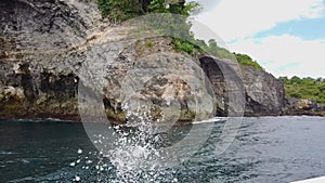 The boat floats past the living rocks, beautiful rocks on the shore in Bali