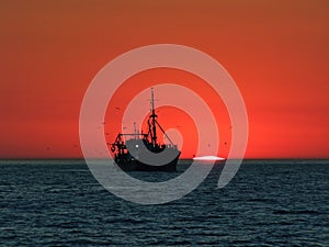 Boat in front of a sunset at the horizon