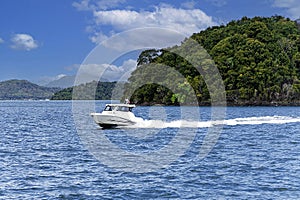 A boat at high speed passes the islands in the Andaman Sea near Phuket,