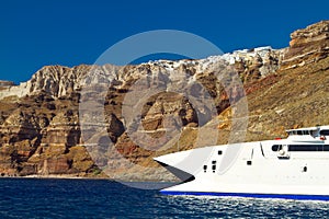 Boat at high volcanic cliff of Santorini island