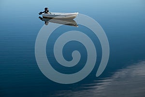 A boat and its clear symmetry reflection on the lake surface.