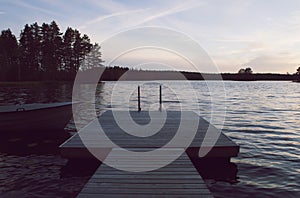 Boat and jetty by lake in beautiful sunset.