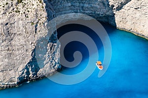 A boat in the lagoon near Navagio Beach, Zakynthos Island, Greece. View of the sea bay and a lone boat from a drone. Blue sea wate