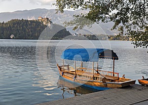 Boat on lake Bled overlooked by castle at sunset.